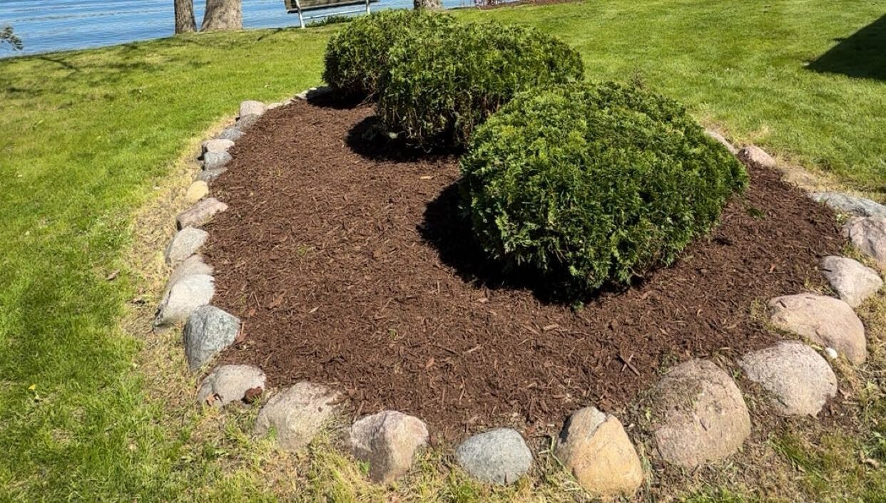 A new flower bed freshly installed. With a stone border and fresh mulch. Landscape Bed Installation​ in Waukesha County